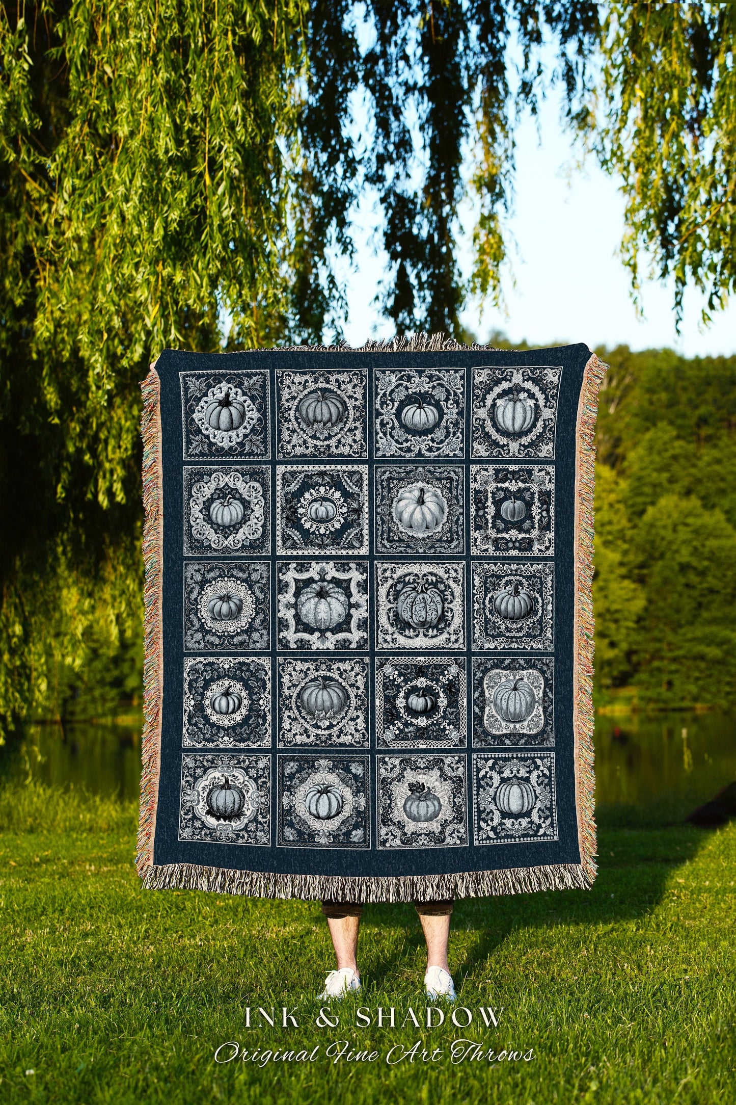 May include: A woven throw blanket with a navy blue background and a white design of repeating pumpkin patterns in ornate frames. The text 'INK & SHADOW Original Fine Art Throws' is at the bottom of the blanket.