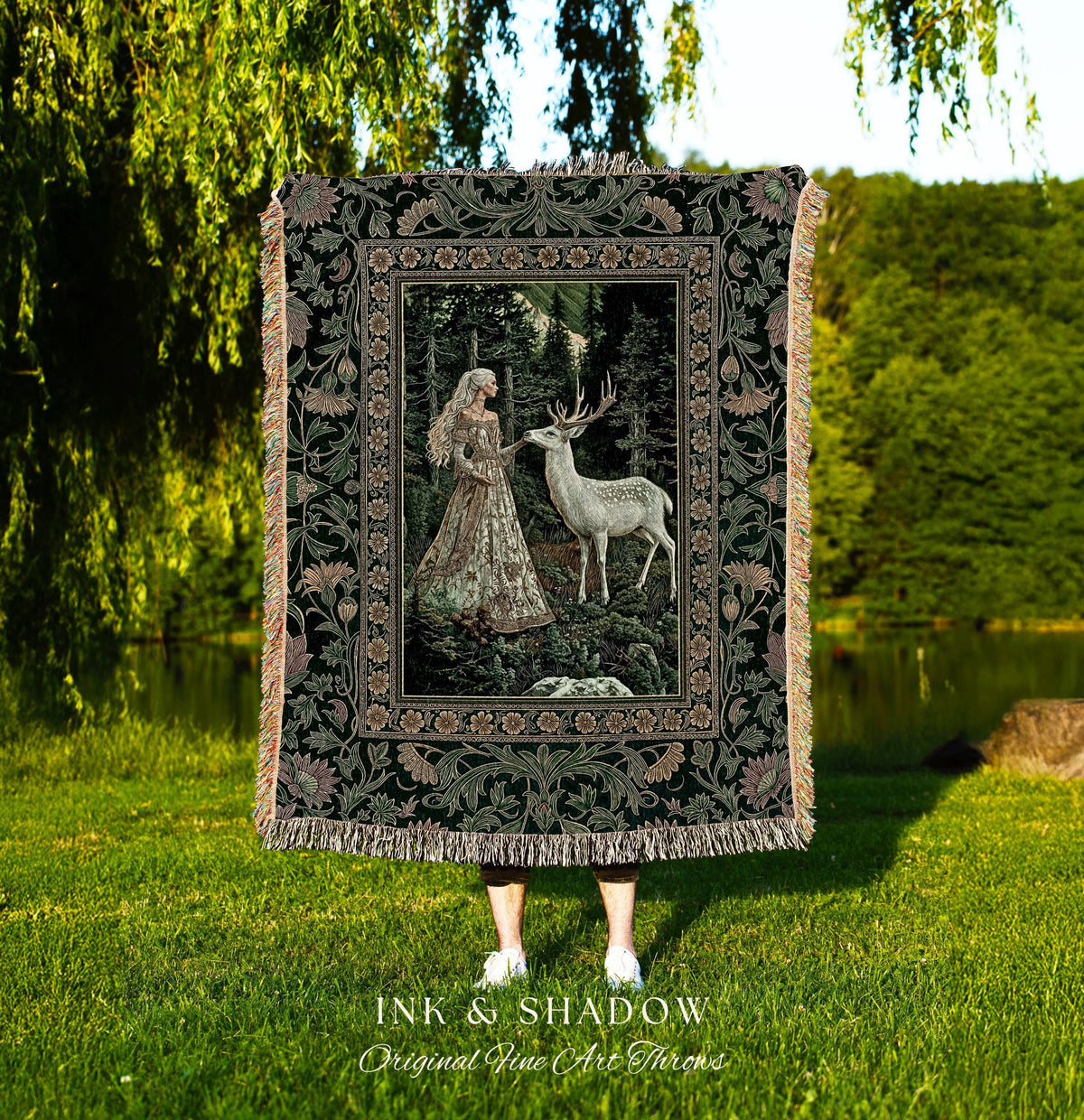 May include: A tapestry throw blanket featuring a forest scene with a woman and a deer. The blanket has a dark green floral border and fringe. The text "INK & SHADOW Original Fine Art Throws" is at the bottom.