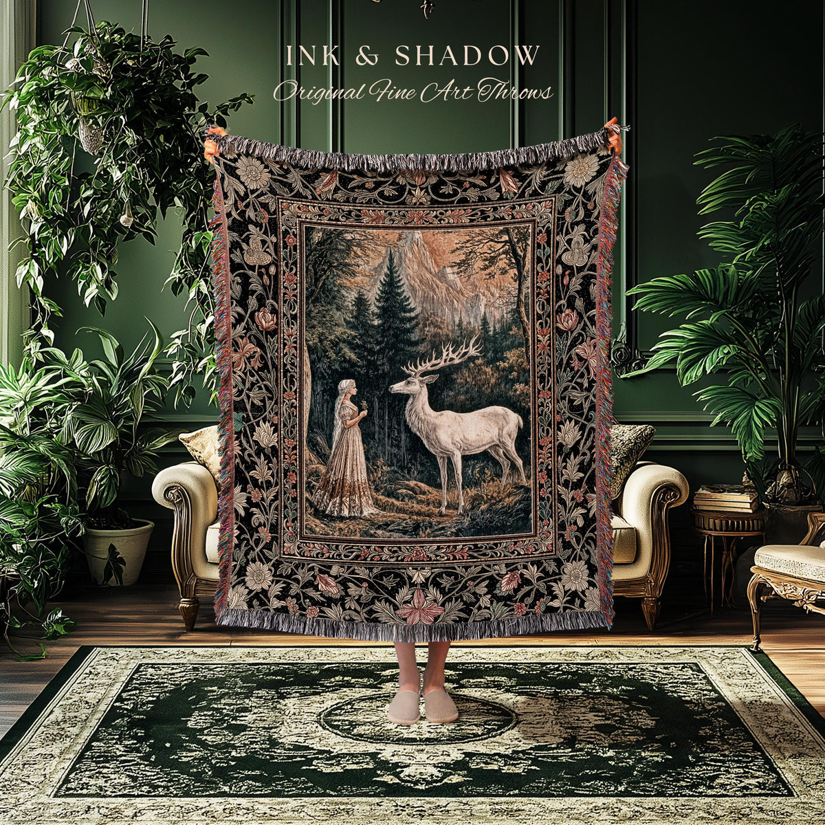May include: A tapestry throw blanket with a forest scene featuring a woman and a white deer. The throw has a black border with floral and leaf patterns, and the text "INK & SHADOW Original Fine Art Throws" is at the top.