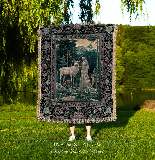 May include: A woven tapestry throw blanket with a dark green, black, and pink floral border. The center of the blanket features a woman in a white gown standing with a white stag in a forest setting. The text &#39;INK & SHADOW Original Fine Art Throws&#39; is printed below the blanket.