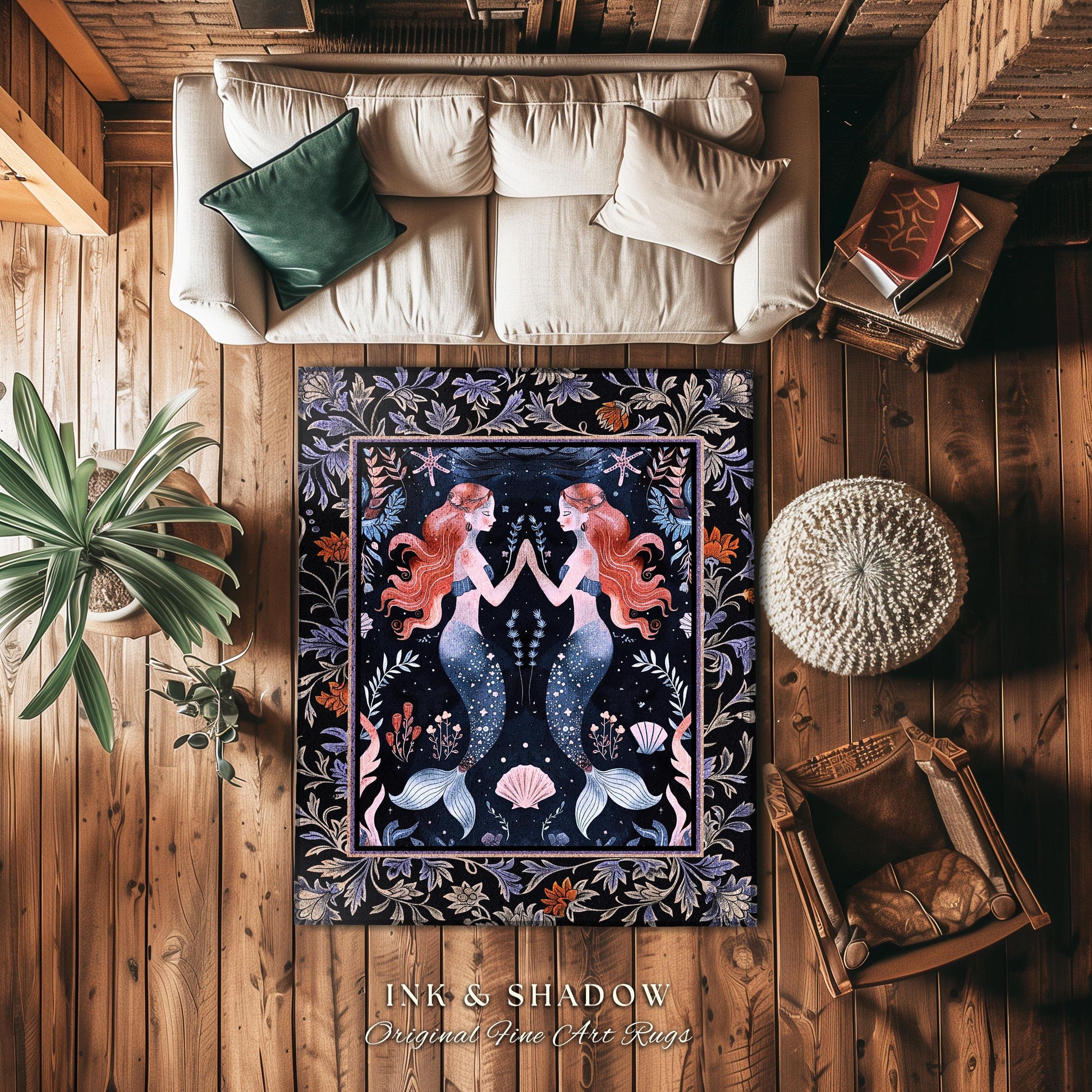 May include: A dark-blue area rug features an illustration of two mirrored mermaids with flowing red hair, surrounded by floral and nautical elements. The rug&#39;s border is decorated with an ornate floral pattern. The text &#39;INK & SHADOW Original Fine Art Rugs&#39; is displayed below the rug.