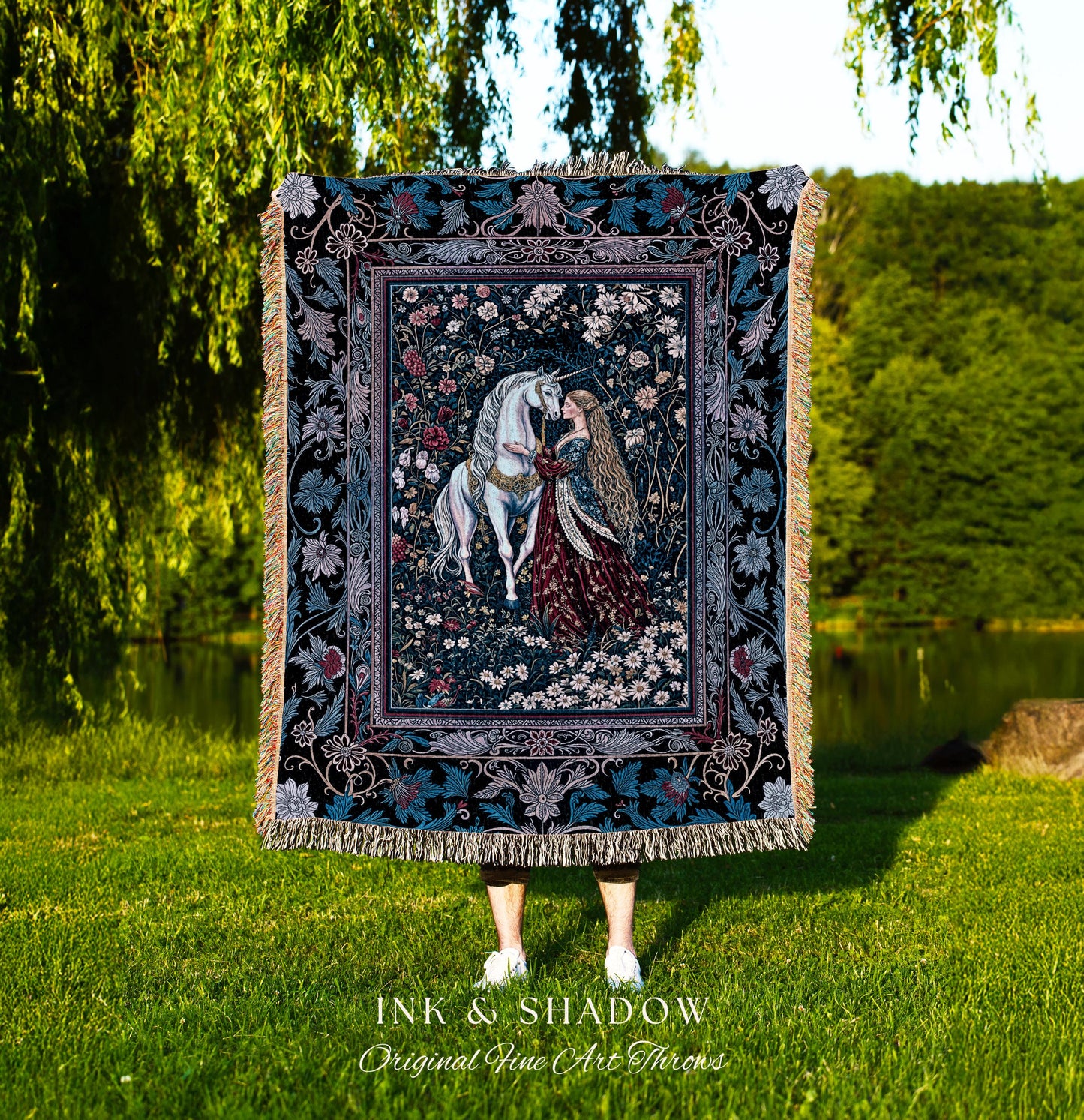 May include: A tapestry throw blanket with a dark blue background and a floral design. The center of the tapestry features a white unicorn and a woman in a red dress. The text &#39;INK & SHADOW Original Fine Art Throws&#39; is printed below the tapestry.