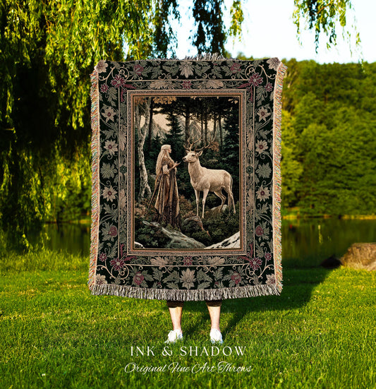 May include: A tapestry throw blanket with a dark green background and a floral border. The center of the tapestry features a woman in a long white dress standing in a forest with a white deer. The tapestry has the words &#39;Ink & Shadow Original Fine Art Throws&#39; at the bottom.