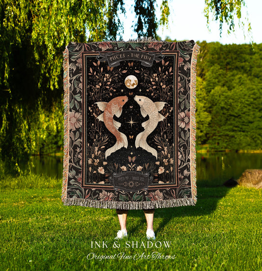 May include: A black woven throw blanket with a floral design and two gold fish. The blanket has a black border with the text &#39;PISCES THE FISH&#39; and &#39;FEB 19-MAR 20&#39; in white. The blanket is displayed in front of a green grassy background. The text &#39;INK & SHADOW Original Fine Art Throws&#39; is displayed below the blanket.