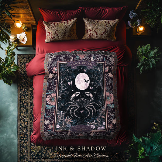 May include: A black and purple woven tapestry with a dark blue background. The tapestry features a stylized crab with a full moon and stars. The tapestry is framed with a floral border and the words &#39;Cancer - The Crab&#39; are printed in white. The tapestry is displayed on a red bedspread with two decorative pillows.