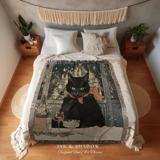 May include: A woven throw blanket featuring a black cat wearing a red bow tie and sitting at a table with a glass of wine. The cat is in front of a window with a snowy scene outside. The blanket has the text &#39;INK & SHADOW Original Fine Art Throws&#39; at the bottom.