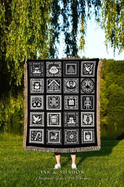 May include: A black woven throw blanket with a white design of 16 squares. Each square has a different Christmas-themed image, including a snowman, a gingerbread man, a Christmas tree, a stocking, a reindeer, a candy cane, and an angel. The text &#39;INK & SHADOW Original Fine Art Throws&#39; is printed below the blanket.