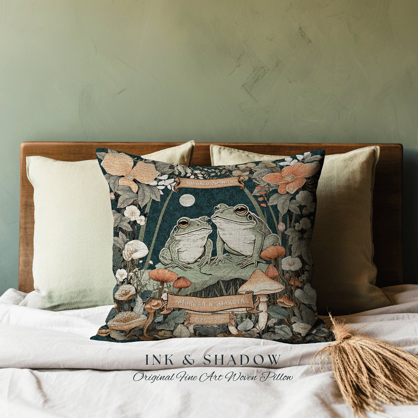 May include: A woven pillow with a dark green background featuring two frogs sitting on a mushroom. The pillow has a floral border and the text 'Together Forever' and 'Morgan & Dakota' in a vintage font. The pillow is labeled 'Ink & Shadow Original Fine Art Woven Pillow'.