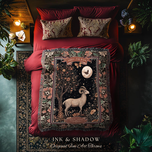 May include: A tapestry throw blanket with a dark background and a floral design. The center of the blanket features a white ram with a crescent moon and stars in the background. The text &#39;Aries - The Ram&#39; is at the top of the blanket. The blanket is displayed on a red bed with two pillows. The text &#39;INK & SHADOW Original Fine Art Throws&#39; is at the bottom of the blanket.