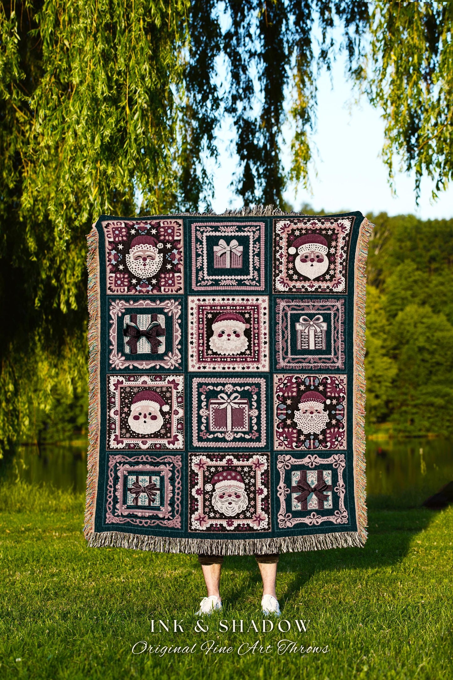 May include: A dark teal woven Christmas throw blanket features a patchwork design of Santa Claus faces and gift boxes in shades of burgundy and cream.  Each motif is framed by a decorative border. The throw has fringed edges. Text at the bottom reads: &#39;INK & SHADOW Original Fine Art Throws&#39;.