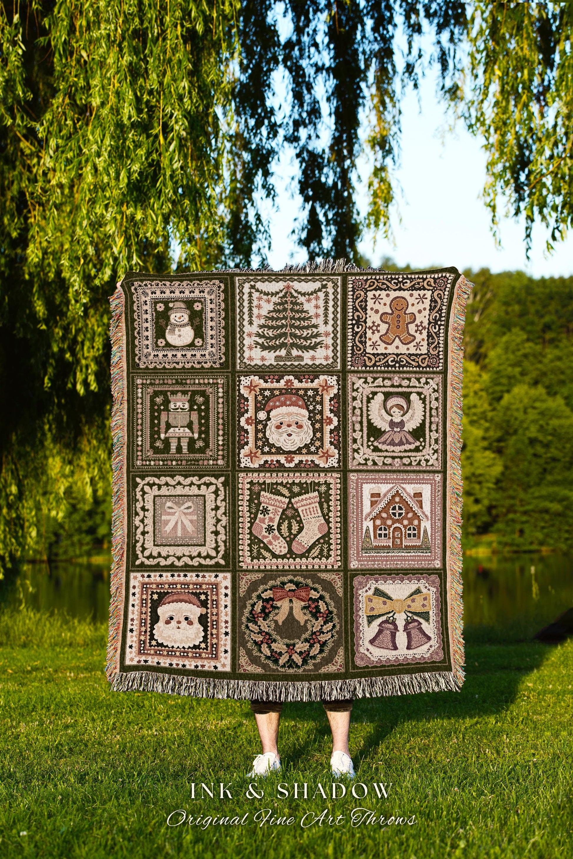 May include: A dark green woven Christmas throw blanket features a patchwork design with various festive motifs.  Each square depicts images such as a snowman, Christmas tree, gingerbread man, Santa Claus, angel, nutcracker, stockings, gingerbread house, Santa&#39;s face, wreath, and bells. The blanket has fringed edges and is displayed against a blurred outdoor background.  The text &#39;INK & SHADOW Original Fine Art Throws&#39; is visible at the bottom.