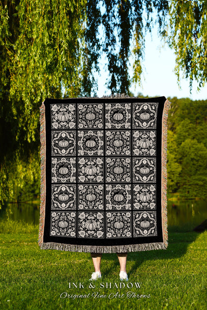 May include: A black woven throw blanket with a white pumpkin pattern. The blanket has a fringe border. The text &#39;INK & SHADOW Original Fine Art Throws&#39; is printed below the blanket.
