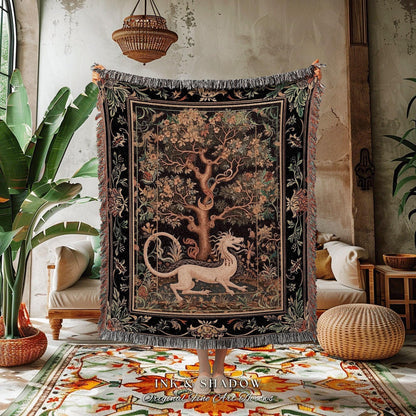 May include: A woven tapestry throw blanket with a black background and a colorful tree of life design. The tree is surrounded by a border of flowers and leaves. A white dragon is curled around the base of the tree. The blanket has fringe on all sides. The text &#39;INK & SHADOW Original Fine Art Throws&#39; is printed on the rug below the blanket.