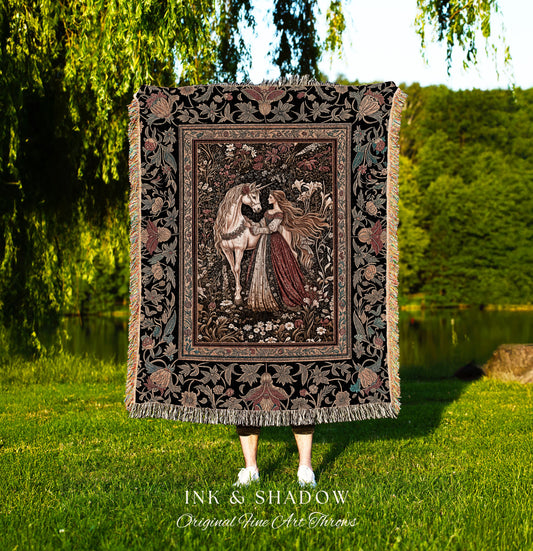 May include: A tapestry throw blanket with a black background and a colorful floral pattern. The center of the blanket features a woman in a red dress with long flowing hair, standing next to a white unicorn in a forest setting. The text &#39;INK & SHADOW Original Fine Art Throws&#39; is printed below the blanket.