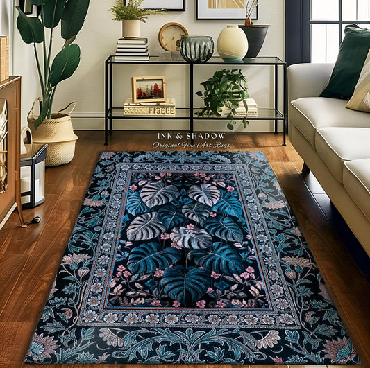 May include: A dark blue rug with a floral pattern. The rug has a light blue and pink floral border and a central design of large, teal leaves. The rug is on a wooden floor in a living room setting. The text on the rug reads &#39;INK & SHADOW Original Fine Art Rugs.&#39;