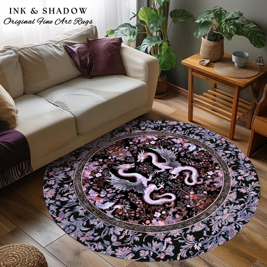 May include: A round rug with a black background and a pink and white floral design. Two pink and white dragons are facing each other in the center of the rug. The rug is surrounded by a black border with a floral design. The text &#39;INK & SHADOW Original Fine Art Rugs&#39; is in the top left corner of the image.