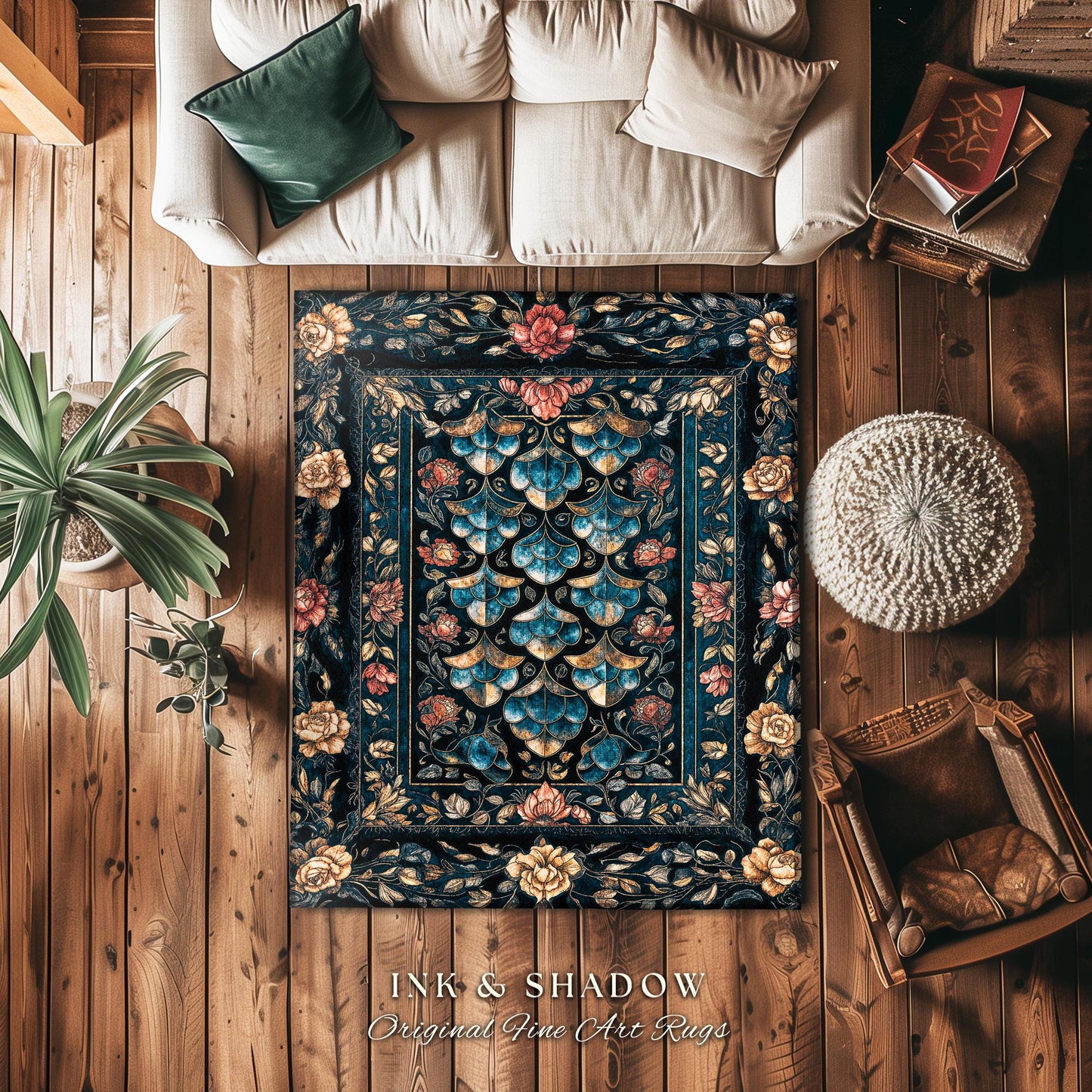 May include: A dark blue rug with a floral pattern. The rug has a border of gold and red flowers. The rug is on a wooden floor with a white couch and a brown ottoman in the background. The rug has the text 'INK & SHADOW Original Fine Art Rugs' at the bottom.
