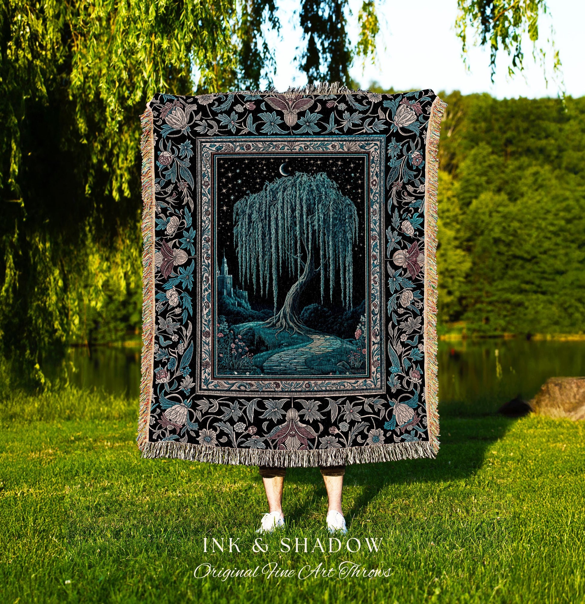 May include: A woven tapestry throw blanket with a black background and a detailed floral border. The center of the blanket features a dark blue willow tree with a crescent moon above it. The tree is surrounded by a dark blue path and a castle in the distance. The text 'INK & SHADOW Original Fine Art Throws' is printed below the blanket.