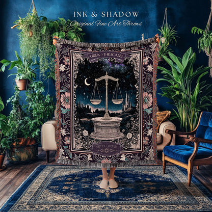 May include: A woven tapestry throw blanket with a dark purple background and intricate floral designs. The center of the blanket features a stylized image of a scale with a crescent moon and stars in the background. The text 'LIBRA THE SCALES' is above the scale and the text 'SEP 23 - OCT 22' is below the scale.
