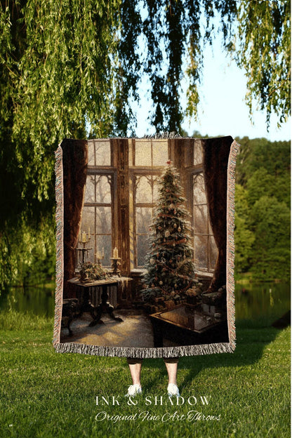 May include: A woven tapestry throw blanket with a Christmas scene. The scene depicts a Christmas tree in a room with a large window. The room is decorated with candles and other holiday decor. The throw blanket is brown and beige with a fringed edge. The text 'INK & SHADOW Original Fine Art Throws' is printed on the bottom of the blanket.