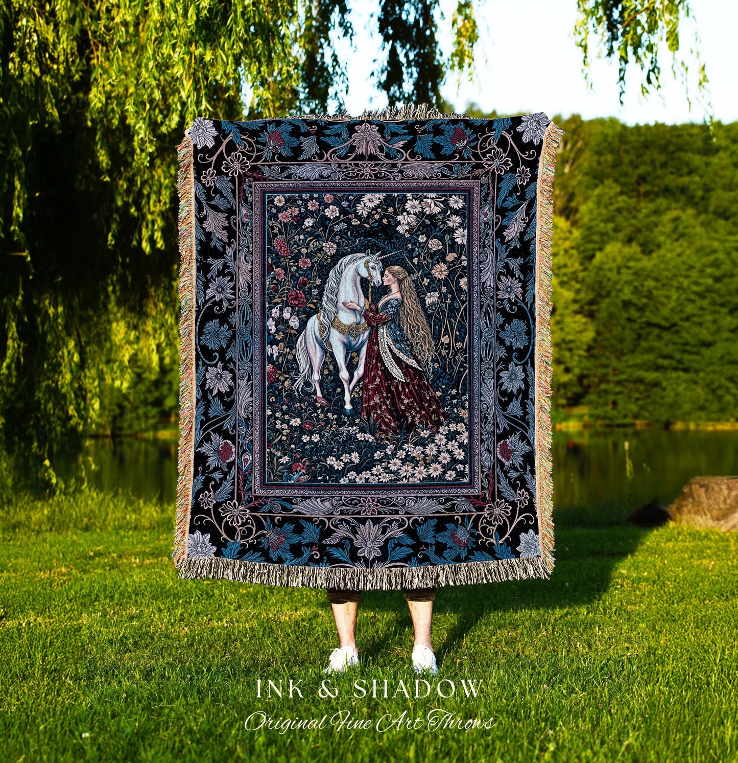 May include: A tapestry throw blanket with a dark blue background and a floral design. The center of the tapestry features a white unicorn and a woman in a red dress. The text 'INK & SHADOW Original Fine Art Throws' is printed below the tapestry.