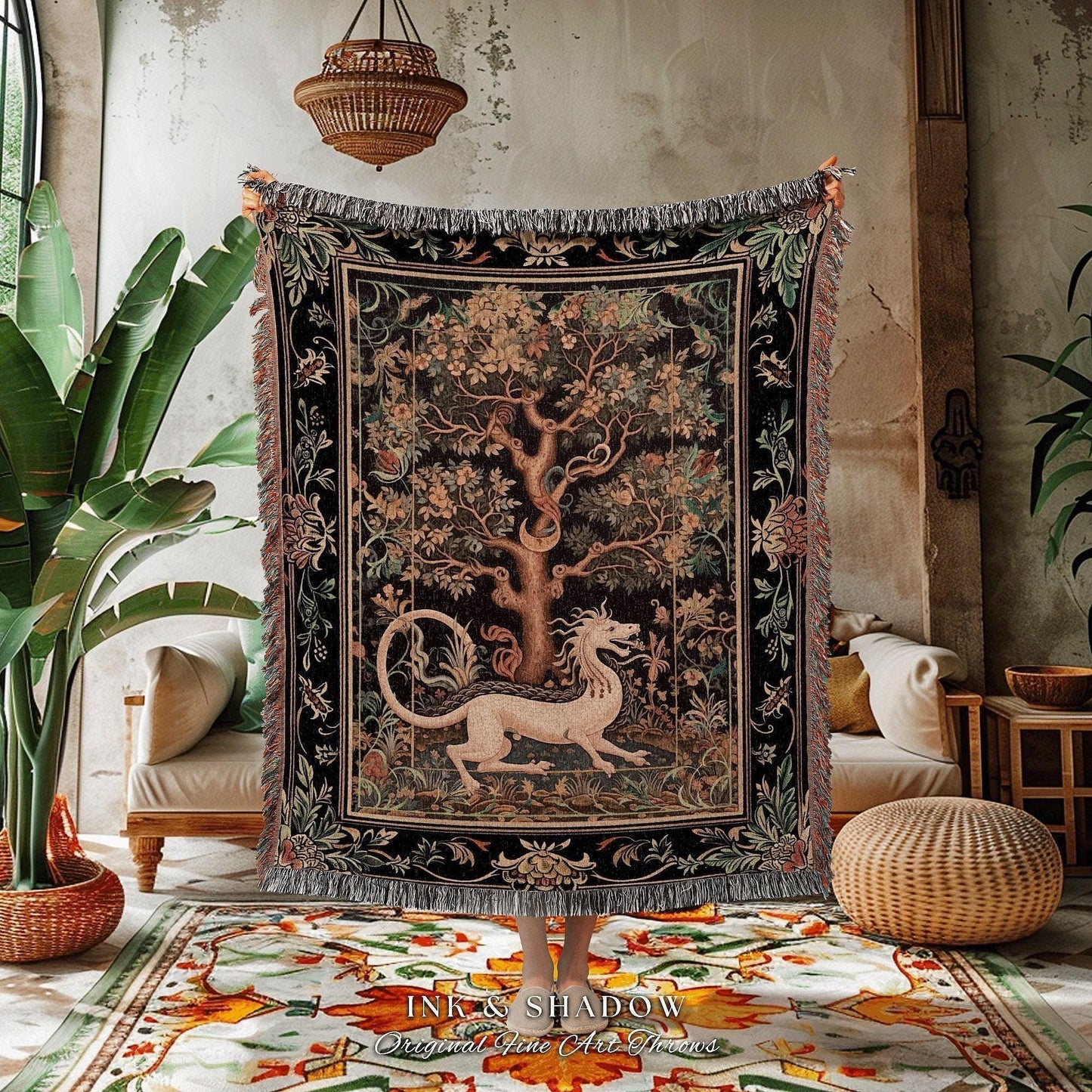 May include: A woven tapestry throw blanket with a black background and a colorful tree of life design. The tree is surrounded by a border of flowers and leaves. A white dragon is curled around the base of the tree. The blanket has fringe on all sides. The text 'INK & SHADOW Original Fine Art Throws' is printed on the rug below the blanket.