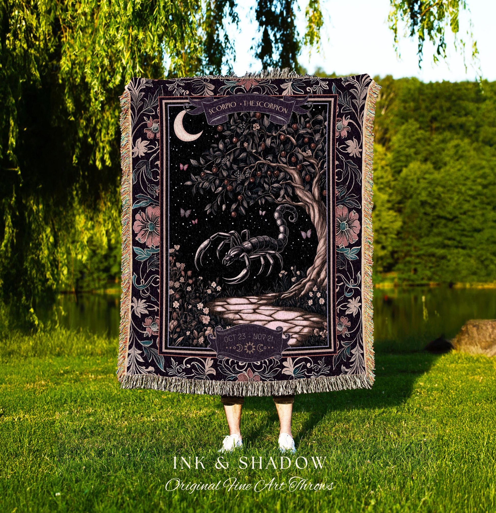 May include: A tapestry throw blanket with a black scorpion design. The scorpion is surrounded by a dark green tree with a crescent moon in the background. The tapestry has a floral border with pink and purple flowers. The text on the tapestry reads 'Scorpio - The Scorpion' and 'Oct 23 - Nov 21'. The tapestry is made by Ink & Shadow Original Fine Art Throws.