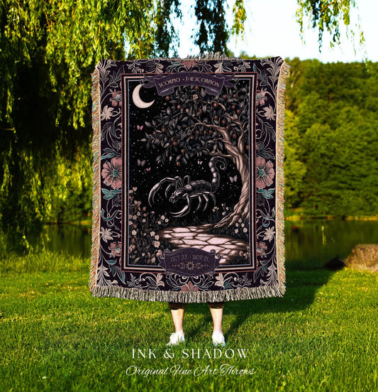 May include: A tapestry throw blanket with a black scorpion design. The scorpion is surrounded by a dark green tree with a crescent moon in the background. The tapestry has a floral border with pink and purple flowers. The text on the tapestry reads 'Scorpio - The Scorpion' and 'Oct 23 - Nov 21'. The tapestry is made by Ink & Shadow Original Fine Art Throws.