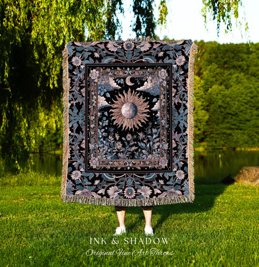 May include: A decorative throw blanket with a celestial design featuring a sun, moon, and floral elements. The blanket has a black background with teal and beige accents, and a fringed edge. The text "INK & SHADOW Original Fine Art Throws" is at the bottom.