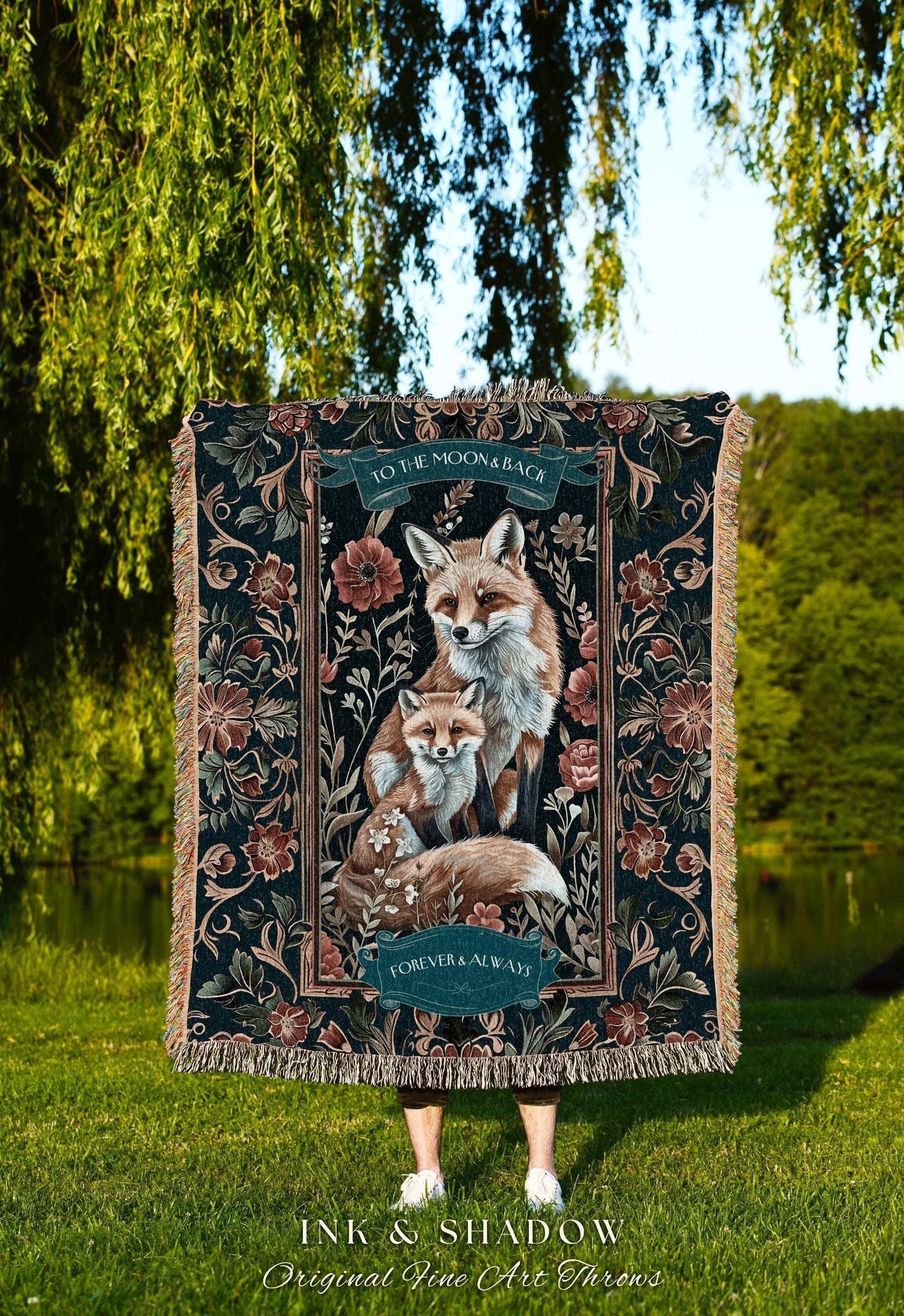 May include: A decorative throw blanket featuring a family of foxes in shades of brown and white, set against a dark floral background. The blanket has the text "TO THE MOON & BACK" and "FOREVER & ALWAYS". The brand name "INK & SHADOW" is also visible.