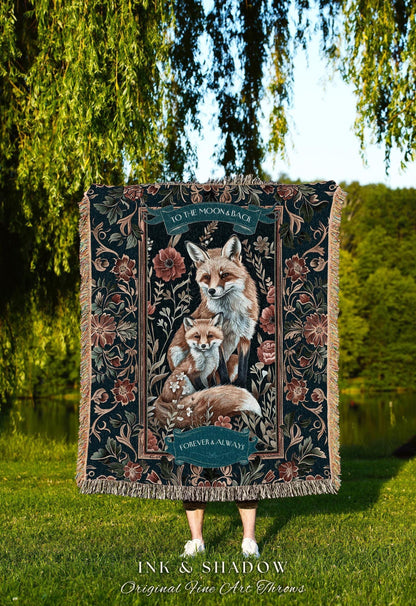 May include: A decorative throw blanket featuring a family of foxes in shades of brown and white, set against a dark floral background. The blanket has the text "TO THE MOON & BACK" and "FOREVER & ALWAYS". The brand name "INK & SHADOW" is also visible.