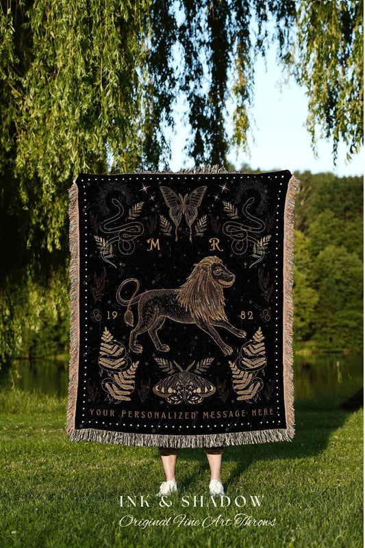 May include: A black woven tapestry with a gold lion, snakes, butterflies, and moths. The tapestry has the letters 'M' and 'R' at the top. The numbers '19' and '82' are on either side of the lion. The text 'YOUR PERSONALIZED MESSAGE HERE' is at the bottom. The text 'INK & SHADOW Original Fine Art Throws' is below the tapestry.