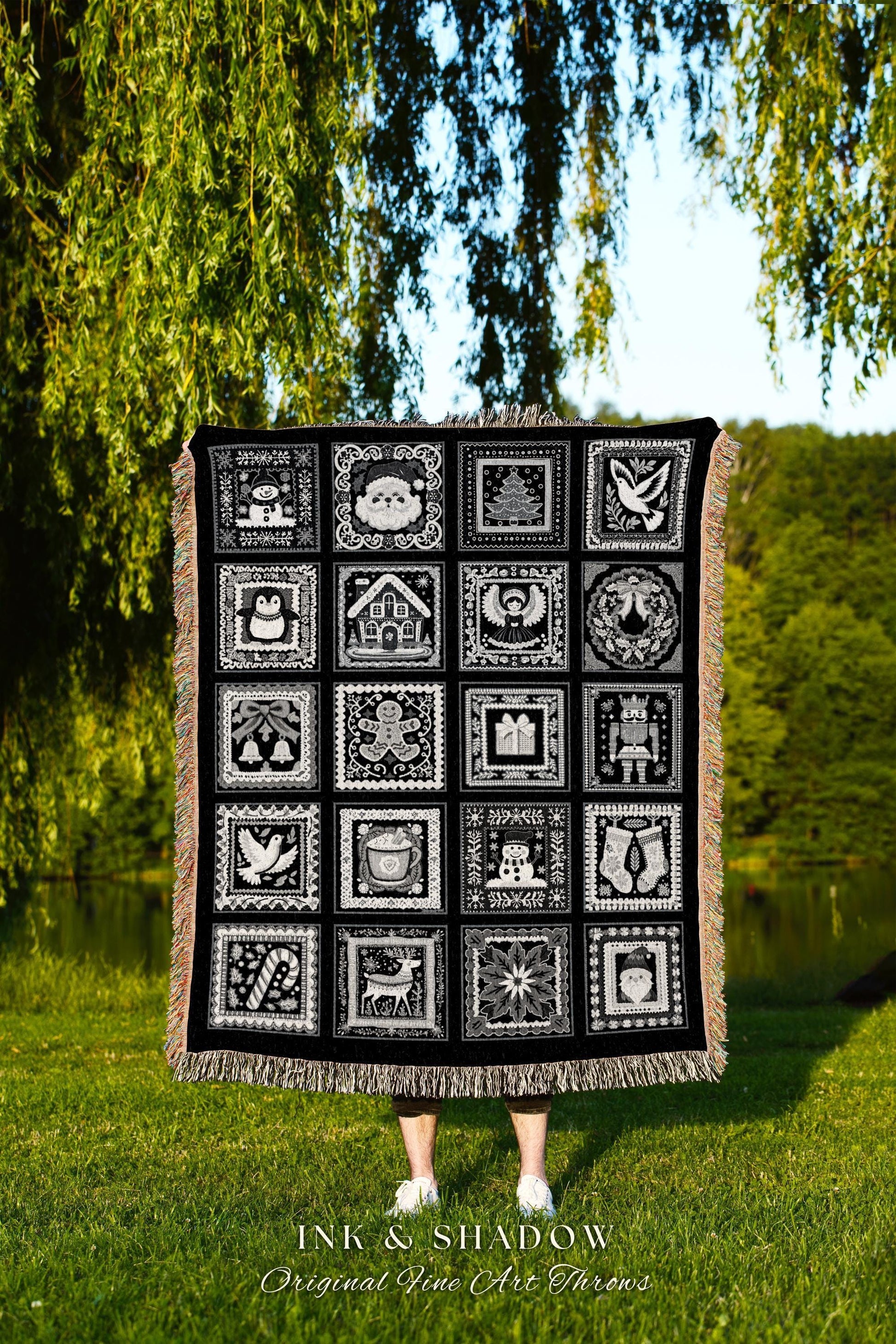 May include: A black woven throw blanket with a white design of 16 squares. Each square has a different Christmas-themed image, including a snowman, a gingerbread man, a Christmas tree, a stocking, a reindeer, a candy cane, and an angel. The text 'INK & SHADOW Original Fine Art Throws' is printed below the blanket.