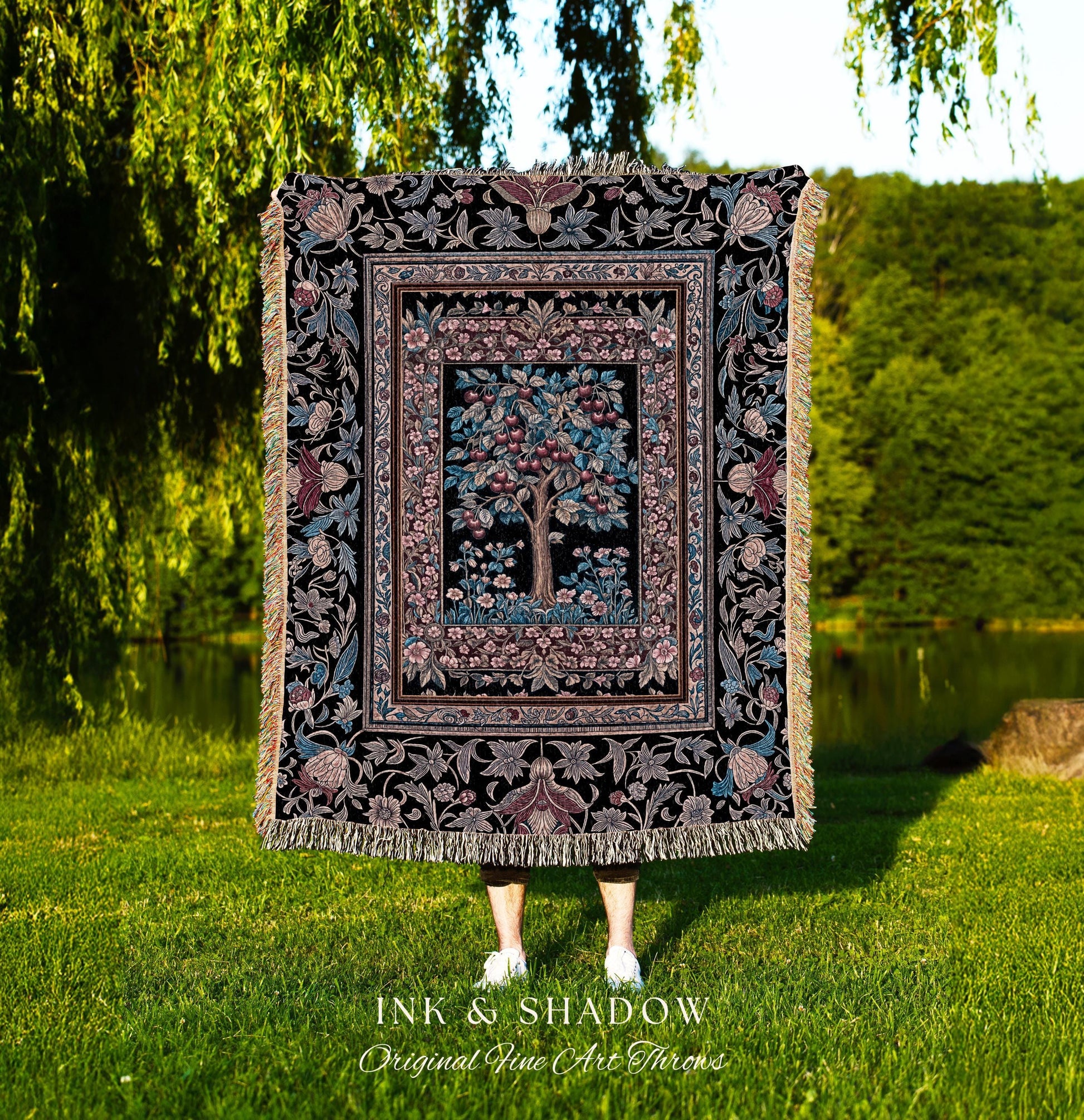 May include: A woven tapestry throw blanket with a black background and a colorful floral pattern. The center of the blanket features a tree with red and blue fruit. The blanket has fringe along the edges. The text 'INK & SHADOW Original Fine Art Throws' is visible at the bottom of the image.