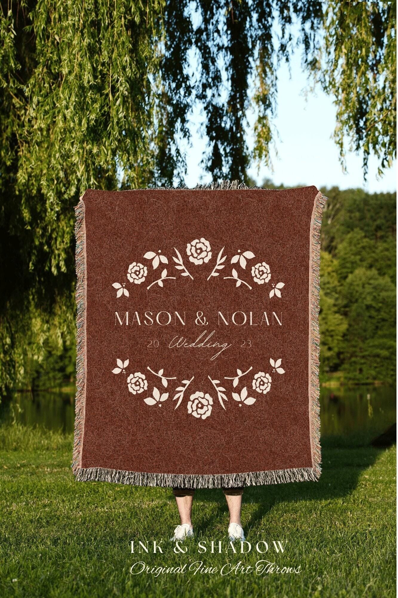 May include: A woven tapestry throw blanket with a maroon background and a white floral design. The text 'MASON & NOLAN 20 Wedding 23' is in the center of the blanket. The text 'INK & SHADOW Original Fine Art Throws' is below the blanket.
