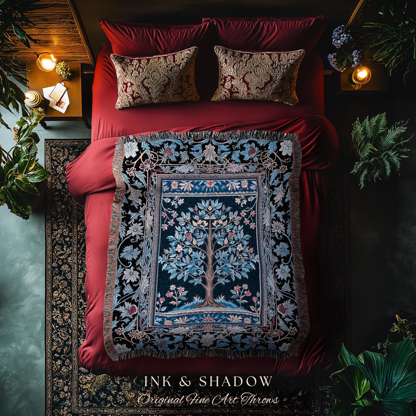 May include: A decorative throw blanket with a tree of life design, in shades of blue, green, and brown, is displayed on a red bed. The blanket is fringed and has a detailed floral border. The text "INK & SHADOW Original Fine Art Throws" is at the bottom.
