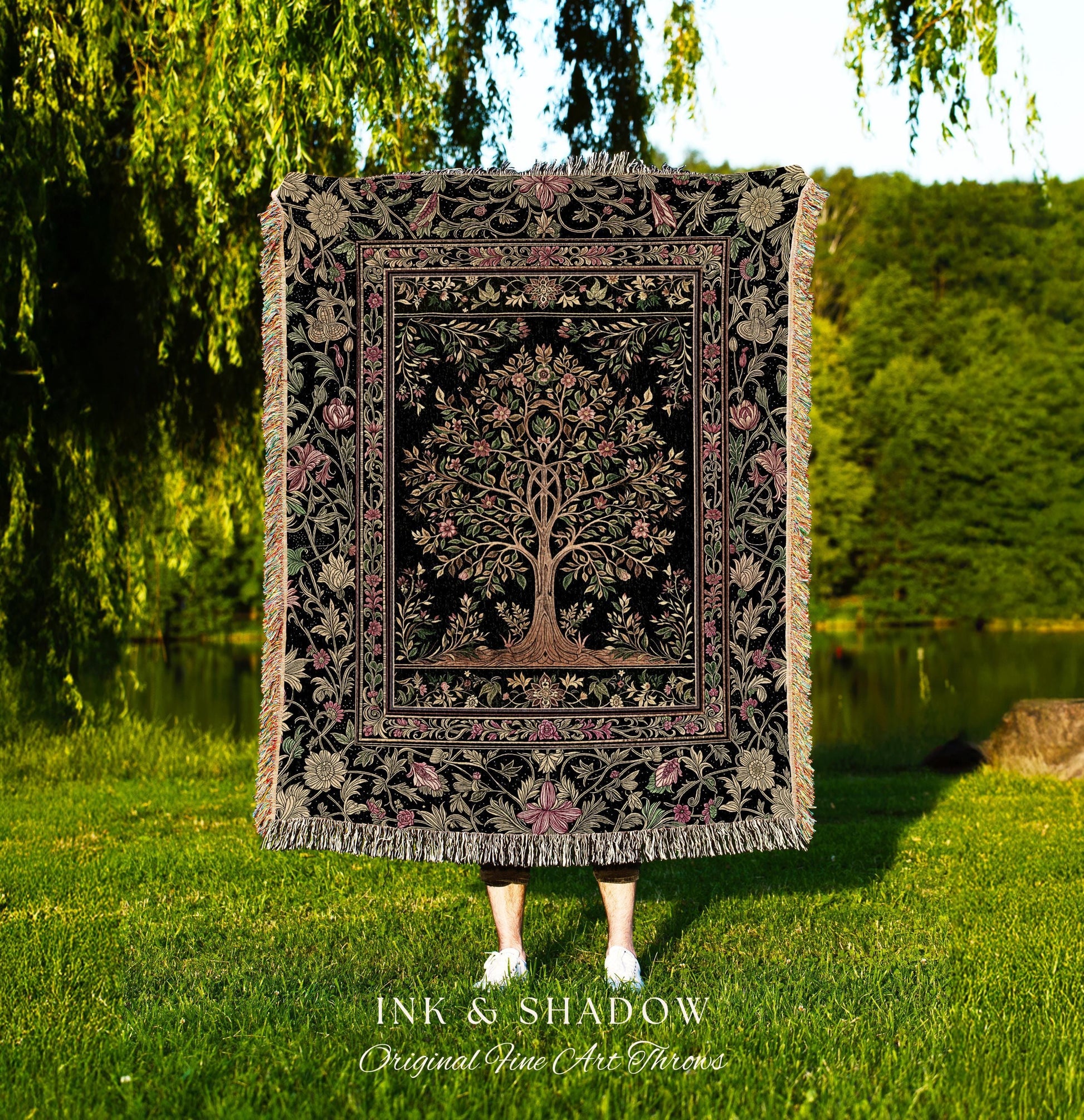 May include: A black throw blanket with a tree of life design, framed by floral patterns in pink, green, and beige. The blanket has a fringed edge and the text "INK & SHADOW Original Fine Art Throws" at the bottom.
