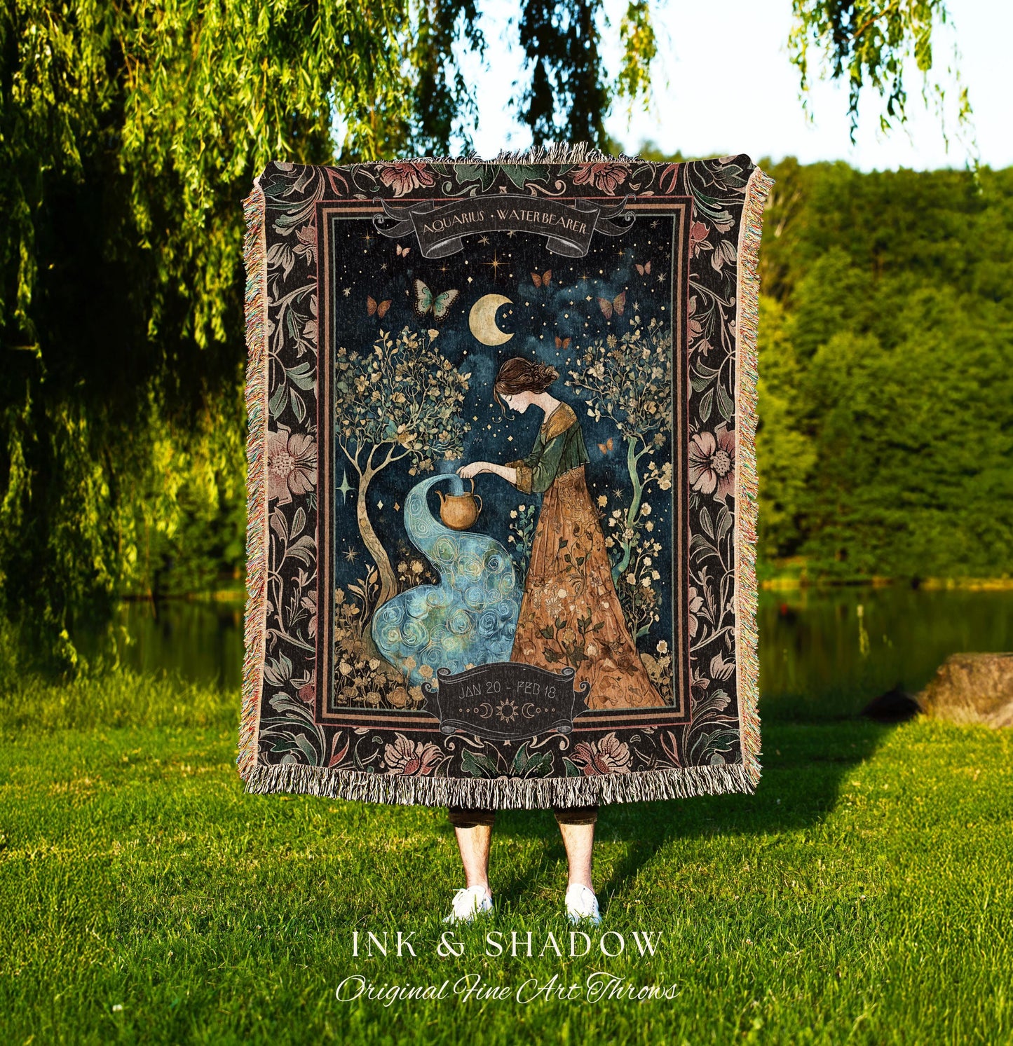 May include: A woven tapestry throw blanket with a dark background and a floral border. The center of the blanket features a woman pouring water from a pitcher into a stream. The stream is surrounded by flowers and butterflies. The text 'Aquarius Waterbearer' is at the top of the blanket. The text 'Jan 20 - Feb 18' is at the bottom of the blanket. The text 'Ink & Shadow Original Fine Art Throws' is at the bottom of the blanket.