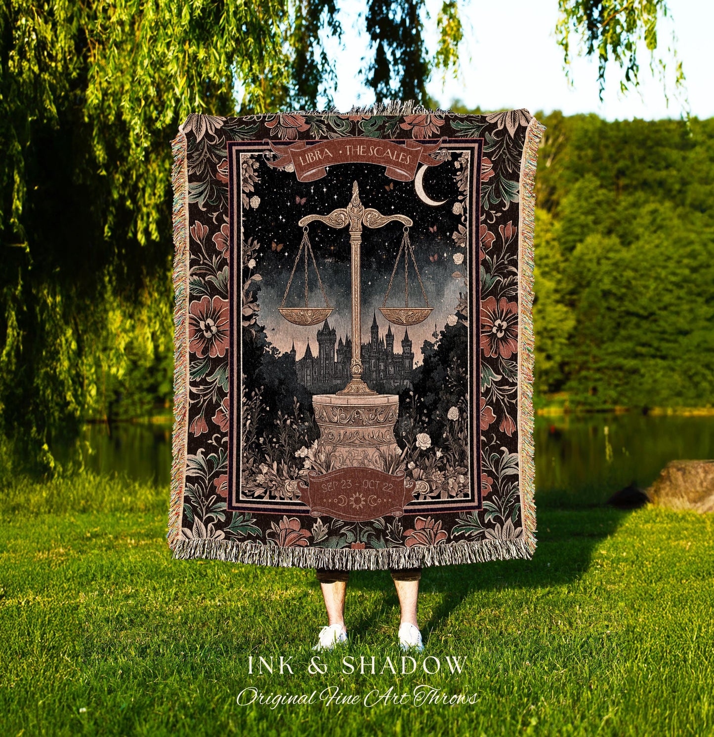 May include: A woven tapestry throw blanket with a dark background and a floral border. The center of the blanket features a black and white illustration of a scale with the text 'Libra - The Scales' and 'Sept 23 - Oct 22'.