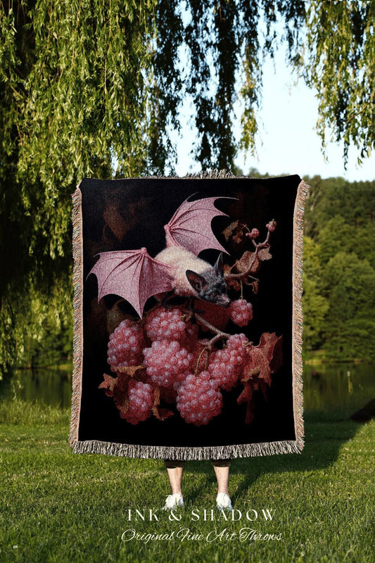 May include: Black throw blanket featuring a bat with pink wings and a cluster of pink berries. The blanket has a fringed edge and the text "INK & SHADOW Original Fine Art Throws" at the bottom.