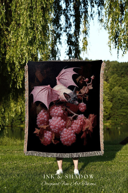 May include: Black throw blanket featuring a bat with pink wings and a cluster of pink berries. The blanket has a fringed edge and the text "INK & SHADOW Original Fine Art Throws" at the bottom.