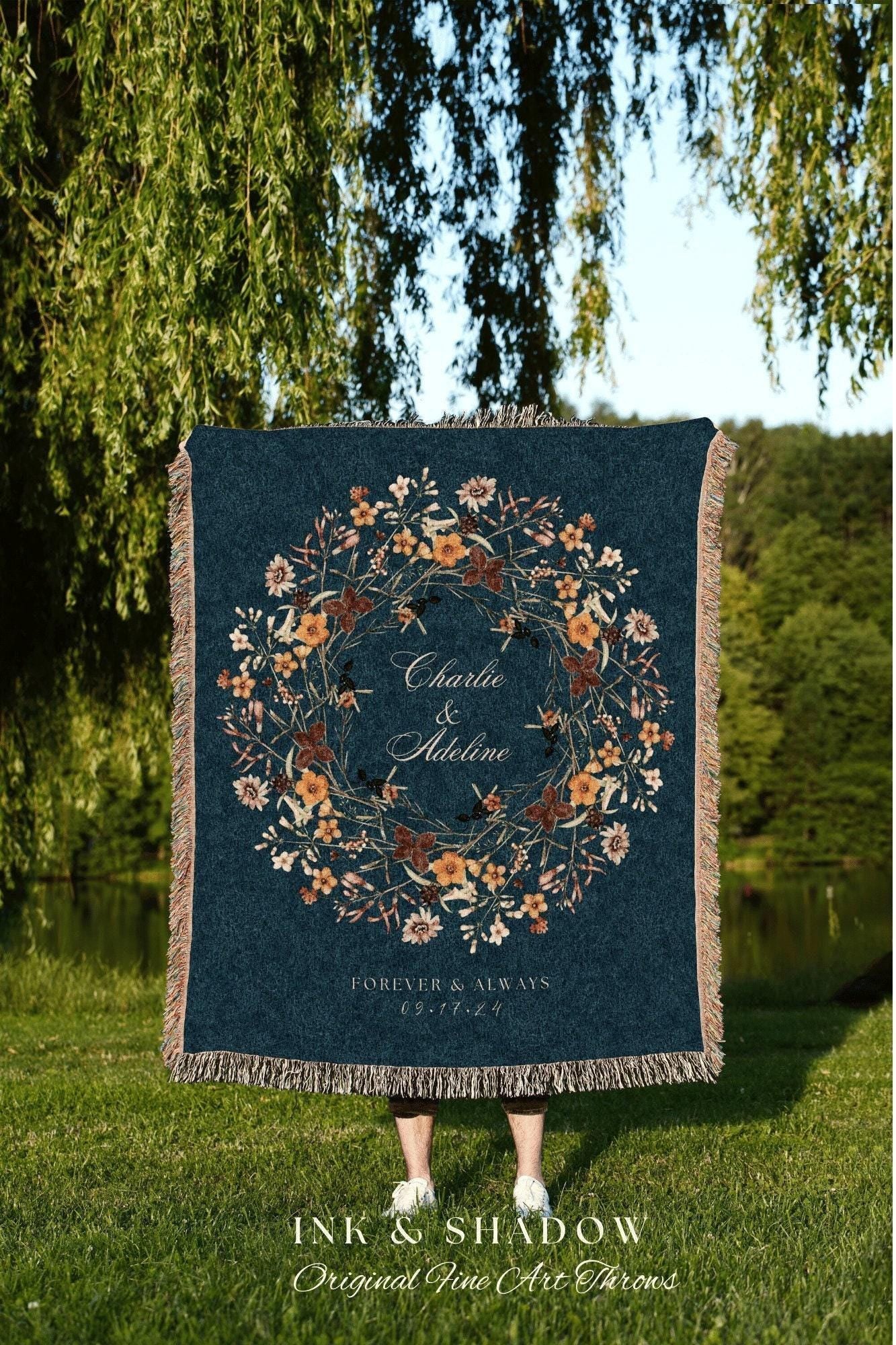 May include: A woven throw blanket with a dark blue background and a floral wreath design in shades of orange, yellow, and brown. The wreath encircles the text 'Charlie & Adeline' and 'FOREVER & ALWAYS 09.17.24'.