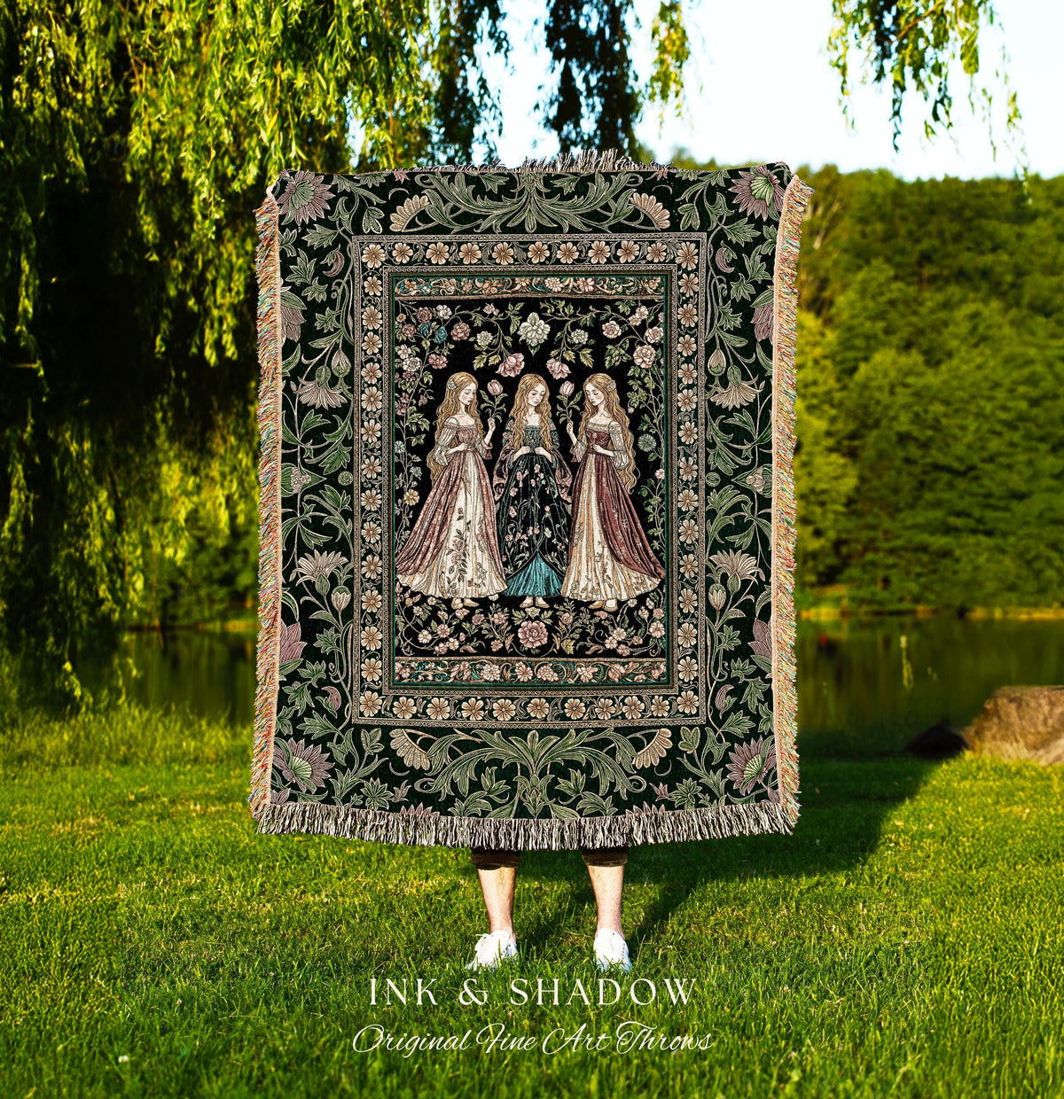 May include: A tapestry throw blanket with a dark green background and a floral border. The center features three women in long gowns. The blanket has a fringed edge and the text "INK & SHADOW Original Fine Art Throws" at the bottom.