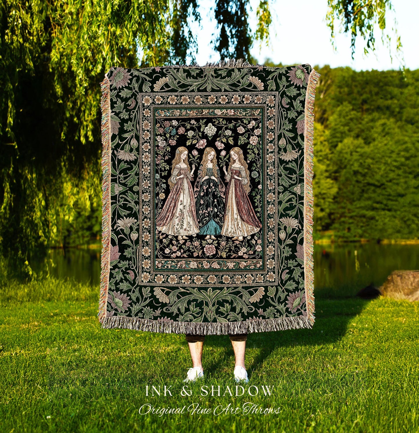May include: A tapestry throw blanket with a dark green background and a floral border. The center features three women in long gowns. The blanket has a fringed edge and the text "INK & SHADOW Original Fine Art Throws" at the bottom.