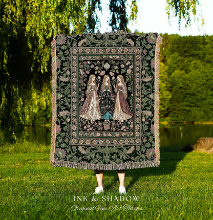 May include: A tapestry throw blanket with a dark green background and a floral border. The center features three women in long gowns. The blanket has a fringed edge and the text "INK & SHADOW Original Fine Art Throws" at the bottom.