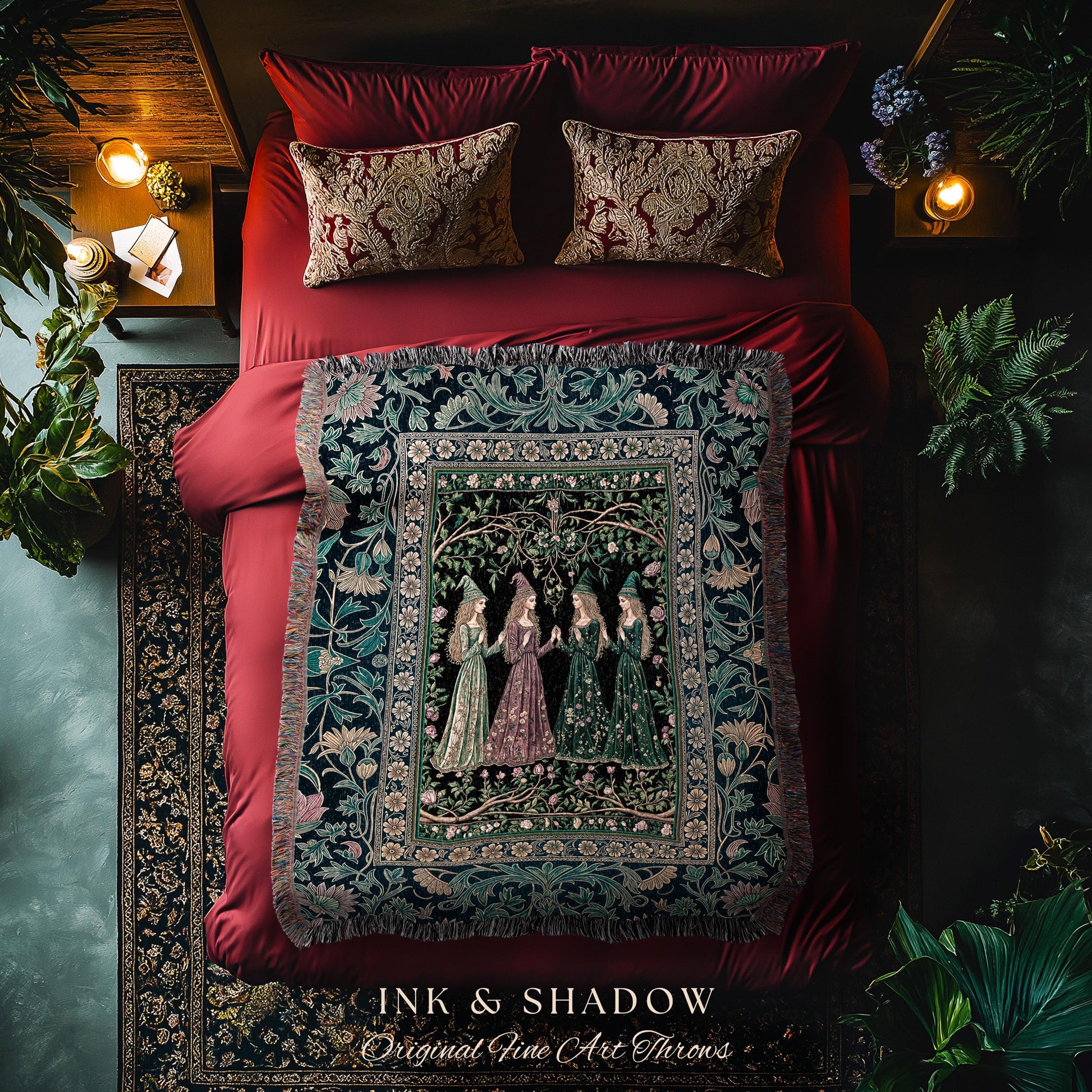 May include: A bed with red bedding, patterned pillows, and a decorative throw blanket. The throw features a detailed illustration of women in gowns. The text "INK & SHADOW Original Fine Art Throws" is at the bottom.