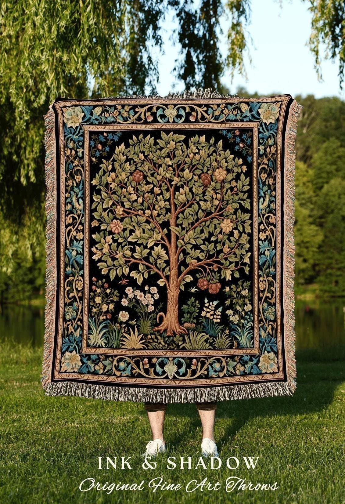 May include: A woven throw blanket with a tree of life design, featuring a black background and a detailed border with floral and foliage patterns. The throw has a fringed edge and the text "INK & SHADOW Original Fine Art Throws".