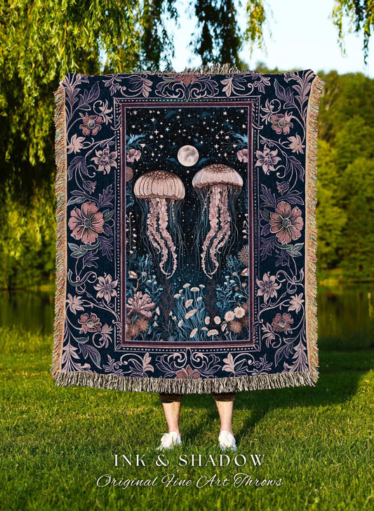 May include: A dark blue throw blanket with a jellyfish design. The blanket features two jellyfish, a full moon, and floral and star details. The text "INK & SHADOW Original Fine Art Throws" is at the bottom. The blanket has a fringed edge.