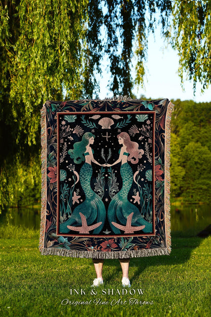May include: A decorative throw blanket featuring a mermaid design. The blanket has a black background with teal mermaids, starfish, and floral accents. The blanket has a fringed edge and the text "INK & SHADOW Original Fine Art Throws".