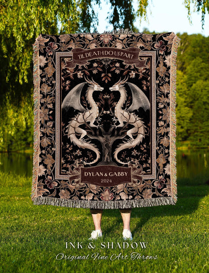 May include: A black throw blanket with a detailed floral and dragon design. The blanket features the text "TIL DEATH DO US PART" and "DYLAN & GABBY 2024". The bottom of the blanket has a fringe. The text "INK & SHADOW Original Fine Art Throws" is at the bottom.